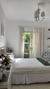 a white bedroom with a bed and a window at CASA DE CAMPO NA CIDADE DA SAÚDE in Serra Negra
