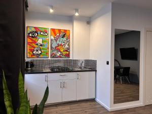 a kitchen with white cabinets and paintings on the wall at POBUUDKA V Plebańska z widokiem na Rynek in Gliwice