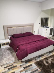 a bedroom with a large bed with a purple comforter at Alhejaz Luxurious Apartment in Cairo