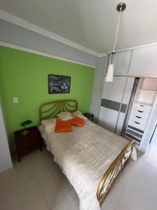 Apartamento Suite en Barquisimeto Muy cómodo y bello في Barquisimeto: غرفة نوم بجدران خضراء وسرير بمخدات برتقالية