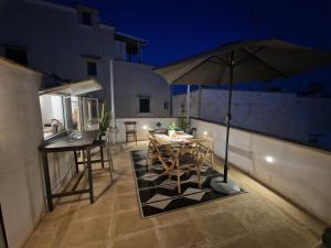 een patio met een parasol en een tafel en stoelen bij Casa Mignano in Gallipoli