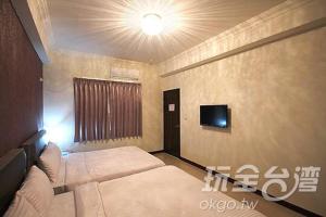 a bedroom with two beds and a tv on the wall at Zih Yue Tong Homestay II in Magong