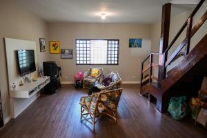 a living room with a couch and a tv and stairs at Chácara Vista para Represa in Mogi das Cruzes