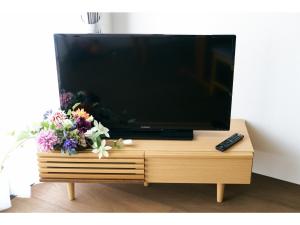 a flat screen tv sitting on a wooden stand with flowers at Tengu Tabine-Cotengu Tabine - Vacation STAY 04455v in Kanazawa