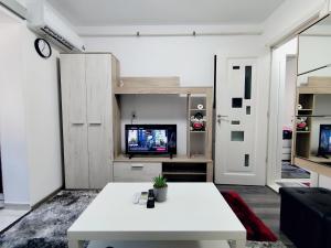 a living room with a white table and a tv at Perla Bocșei - Apartament Etaj 4 in Bocşa