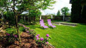 two pink chairs sitting in a yard with flowers at Świerkowe Zacisze Nałęczów in Nałęczów