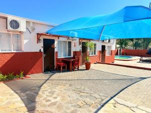 a blue umbrella in front of a house at Ethithiya Swiss Chalets in Windhoek