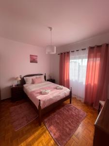 een slaapkamer met een bed met roze gordijnen en een tapijt bij Refúgio do Mar - Peniche in Peniche +7 foto's