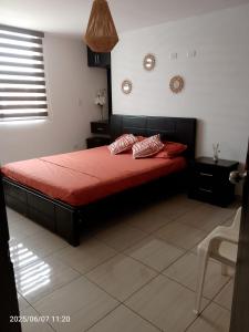 a bedroom with a red bed with two pillows on it at Moderno Apartamento completo 3piscinas 2jacuzzi y Playa cerca in Tonsupa