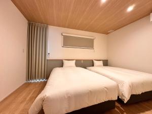 two beds in a room with a window at Aoi Suite Takayama - Vacation STAY 15104v in Takayama