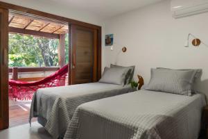 two beds in a room with a window at Casa Carcará a 300 m da praia de Taipu de Fora in Taipu