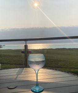 ein Glas Wein auf einem Tisch mit Sonnenuntergang in der Unterkunft 30 Bredon Court Newquay Sea view in Newquay