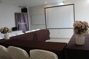 a conference room with tables and chairs and a screen at Paris Senlis Hostel Plus in Chimbote