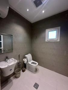 a bathroom with a toilet and a sink and a window at قمم الخضراء  +11 photos
