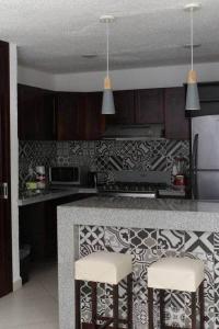 a kitchen with a counter and two bar stools at Las Gaviotas Hotel and Suites in Cancún