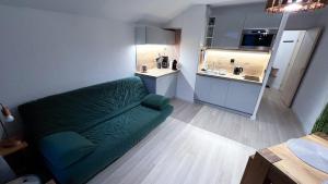 a living room with a green couch and a kitchen at 3 cows in Les Contamines-Montjoie +6 photos