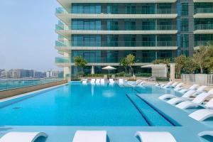 ein Swimmingpool mit Liegestühlen und ein Gebäude in der Unterkunft Luxury 2 Bedroom Apartment - Private Beach - Emaar Beach Vista in Dubai