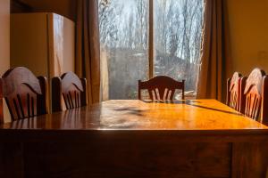 a dining room table with chairs and a large window at Cabaña Finca La Micela - Tupungato in Tupungato