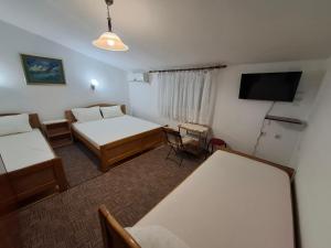 ein Zimmer mit zwei Betten und einem Flachbildfernseher in der Unterkunft Aleksandrija in Čanj
