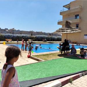 a little girl standing in front of a swimming pool at الشروق 2 résidence chourouk 2 in Mansouria