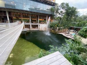 a pond in front of a building with a fountain at Eco chic apartment in Tulum in Tulum