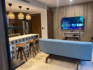 a living room with a blue couch and a tv at Eco chic apartment in Tulum in Tulum