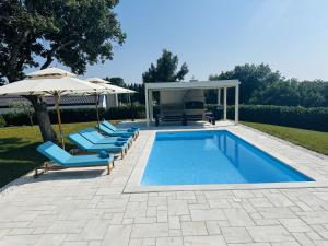 a swimming pool with chairs and an umbrella at Villa V in Svetvinčenat