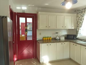 a kitchen with a red door and white cabinets at Villa en Guababerry in Los Conucos