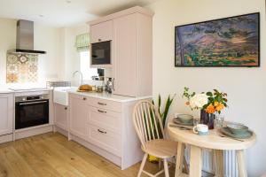 a kitchen with white cabinets and a table with flowers at Wychwood Cottage in Charlbury