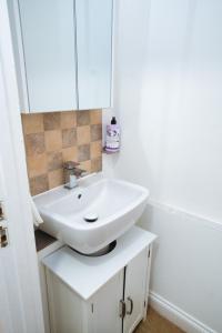 a bathroom with a white sink and a mirror at Home close to city center home in Milton Keynes