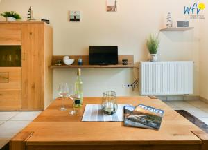 a wooden table with a bottle of wine and wine glasses at Villa Cila Ferienwohnung 3 in Wangerooge