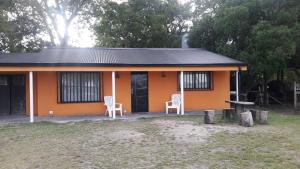 a small orange house with two chairs in front of it at Cabañas La FLorencia in Magdalena