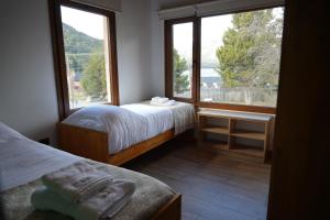サン・カルロス・デ・バリローチェにあるGuti Andino Hostel Boutiqueのベッドが2つと大きな窓がある寝室 +49枚の写真