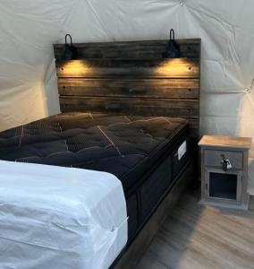 a bed in a room with a wooden wall at Glamping with the Stars, Aquarius in Hadashville