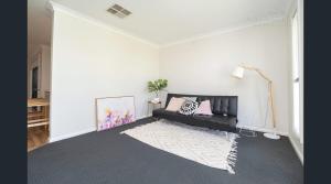a living room with a black couch and a rug at Barooma Escape in North Wagga