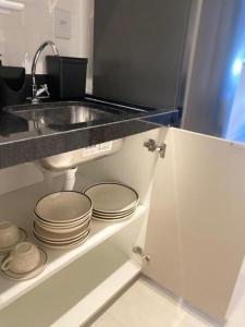 a kitchen with a sink and a bunch of plates at Flat moderno Garagem AR cond Jardim Amália VR in Volta Redonda