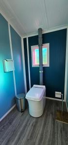 a blue bathroom with a toilet and a window at Glamping with the Stars, Aquarius in Hadashville