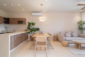 a kitchen and living room with a table and a couch at Kune in Tulum