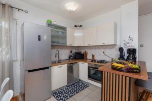 a kitchen with white cabinets and a wooden counter top at Apartments with parking space Duce, Omis - 4663 in Duće +14 photos