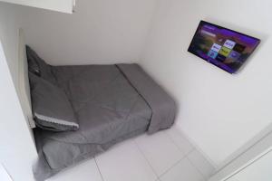 a bed in a room with a tv on the wall at Loft Murano in Paulínia