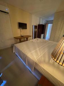 a bedroom with a large white bed and a table at Hotel das Marés in Trairi