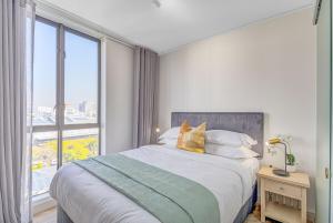 a bedroom with a bed and a large window at One Rosebank- 2 bedroom PentHaus on sixth in Johannesburg