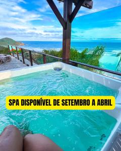 a hot tub with the ocean in the background at Pousada Descanso do Rei - Vista Para o Mar & Melhor Localização da Praia do Rosa in Praia do Rosa