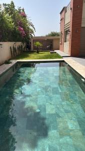 a swimming pool with blue tiles in a yard at Petit Palm in El Rhechat