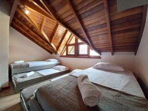 a attic room with two beds and a window at Casa Aconchegante em São Chico in São Francisco de Paula