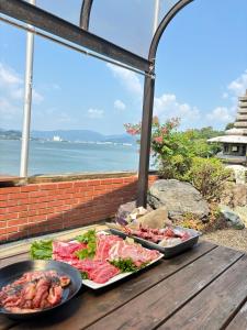 two trays of food on a wooden table with the ocean at MiLiS 自分を取り戻す湖畔の時間 in Ōsaki