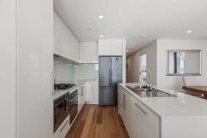 a kitchen with white cabinets and a stainless steel refrigerator at Moritz 1 in Mount Hotham