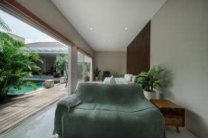 a living room with a green chair and a pool at Villa Lumiere - 3BR Luxury Villa with Private Pool in Seminyak