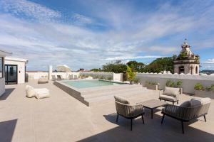 a patio with a pool and chairs and a building at Casco Viejo Loft with Balcony - Rooftop Pool and Gym in Panama City