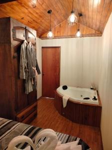 a bathroom with a bath tub and a bed at Chalé Aconchego em Campos in Campos do Jordão